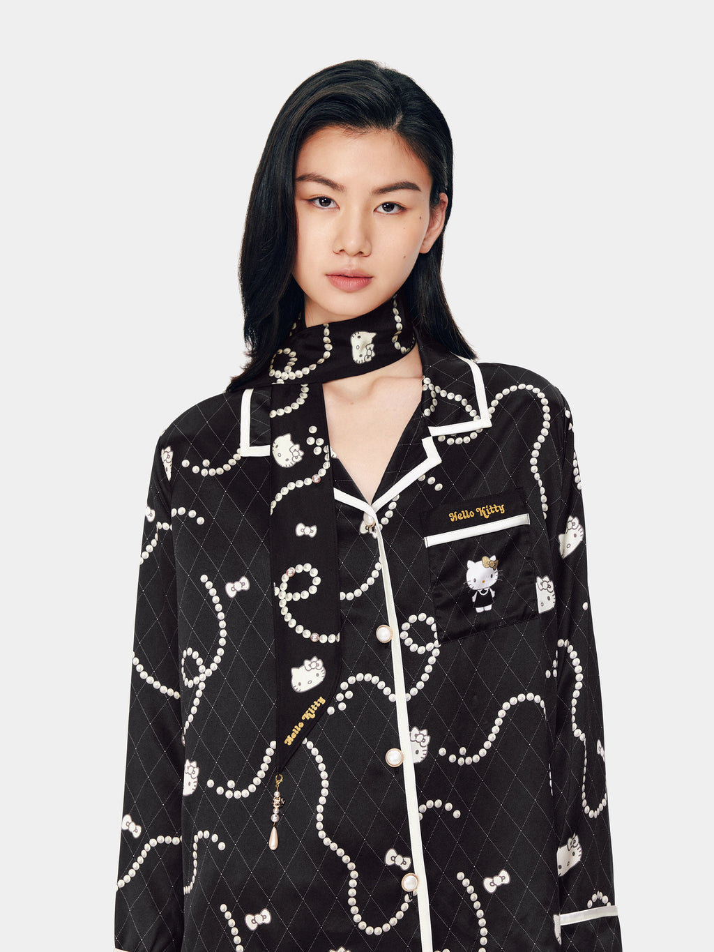 Model styling the tbh home x Hello Kitty silk scarf, featuring a trompe l'oeil pearl necklace print that looks like real jewelry.